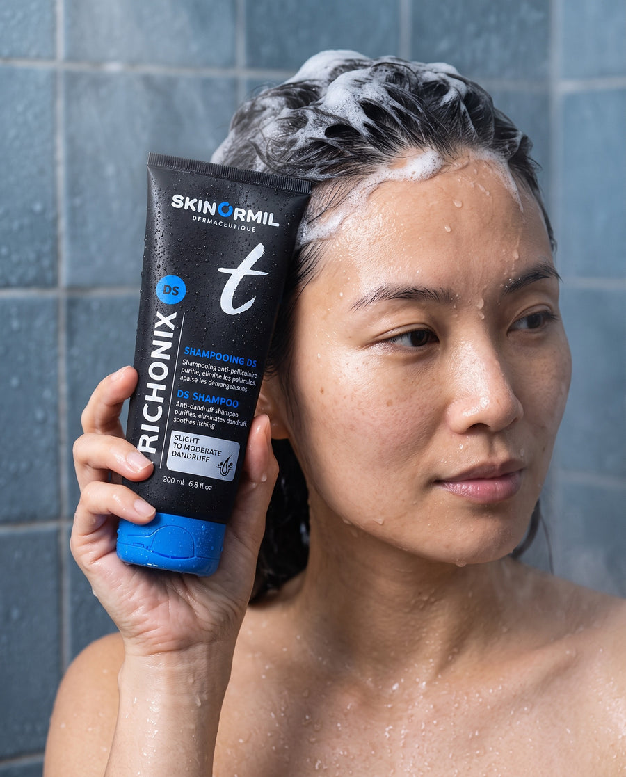 Woman in the shower holding Skinormil Trichonix DS anti-dandruff shampoo